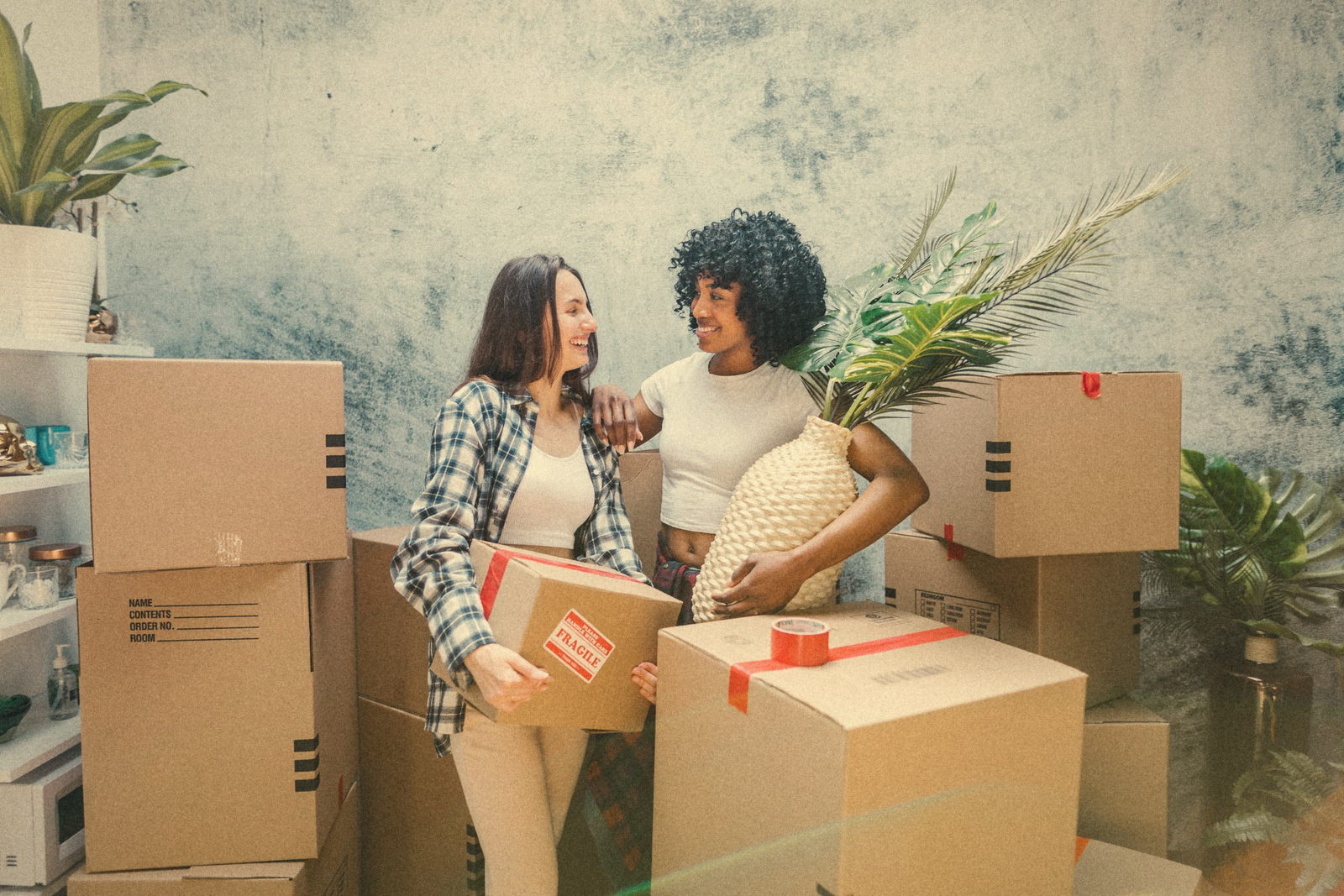 Two friends unpacking moving boxes in their new home